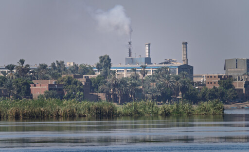 Das Stahlwerk von Edfu in Ägypten mit seinen Industriegebäuden und Schornsteinen, vom Nil aus gesehen. 6. November 2024