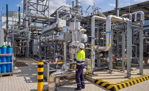 Oberhausen, Nordrhein-Westfalen, Deutschland - Gruener Wasserstoff bei Air Liquide, Wasserstoffproduktion im Chemiepark OQ Chemicals. TRAILBLAZER, ein 20 MW-Elektrolyseur zur Herstellung von gruenem, klimaneutralem Wasserstoff. Eine Ingenieurin steht an der Anlage, regelt an einem Schieberventil den Leitungsdurchfluss.